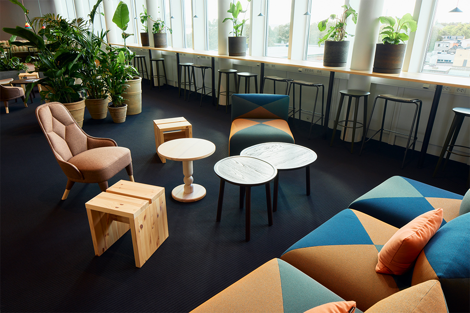 Loungemiljö på ett svenskt kontor med växter, soffor och bardiskar
